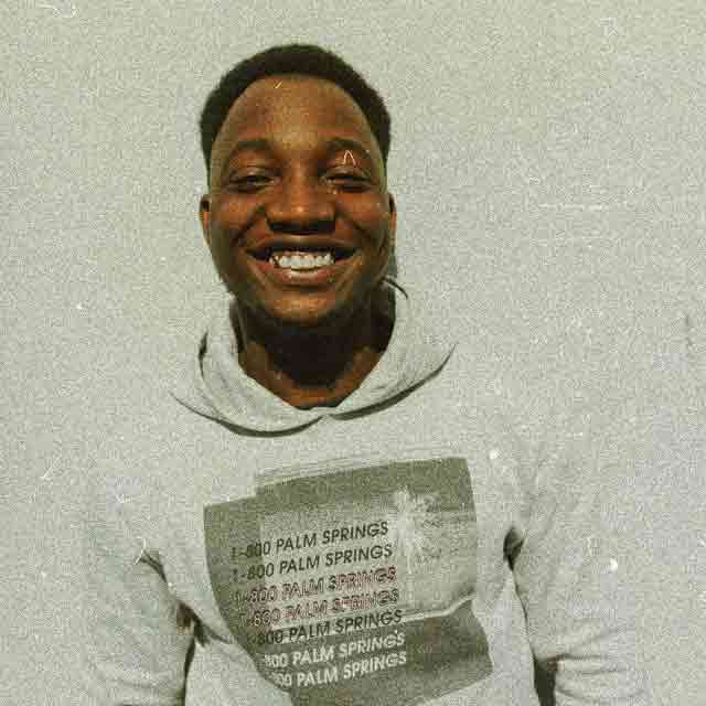 Rico wearing a grey hoodie smiling and posing